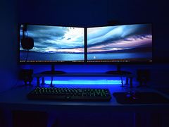 A dual-monitor gaming desk with a backlit mechanical keyboard