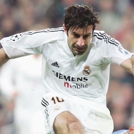 Close-up of a professional footballer in a white kit driving forward with the ball during a match