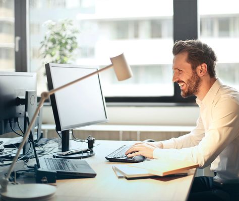 An engineer smiling while working at a dual-monitor desk